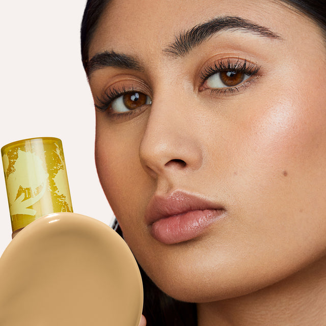 Model wearing Revealer Skin-Improving Foundation SPF 25 in Light Medium Neutral Olive 210