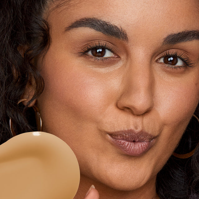 Model wearing Revealer Skin-Improving Foundation SPF 25 in Medium Tan Neutral Olive 260