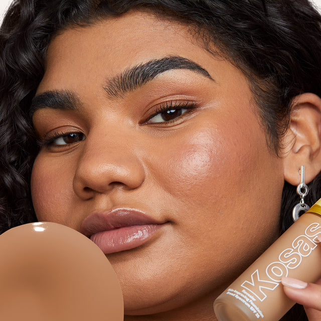 Model wearing Revealer Skin-Improving Foundation SPF 25 in Medium Deep Neutral Cool 310