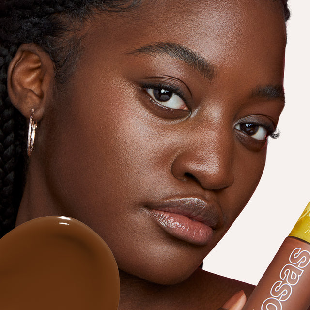 Model wearing Revealer Skin-Improving Foundation SPF 25 in Rich Deep Neutral Olive 430