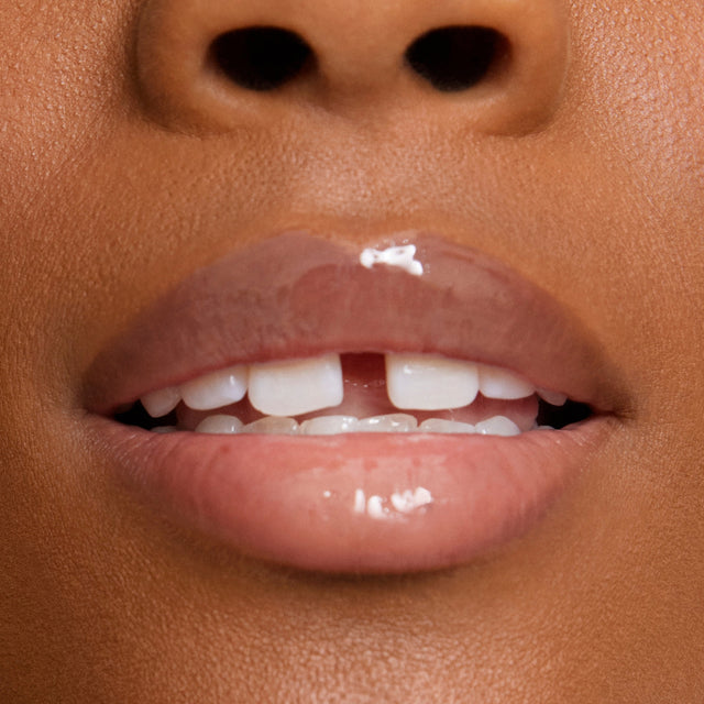 Deep skin tone model wearing Wet Lip Oil Gloss in Jellyfish