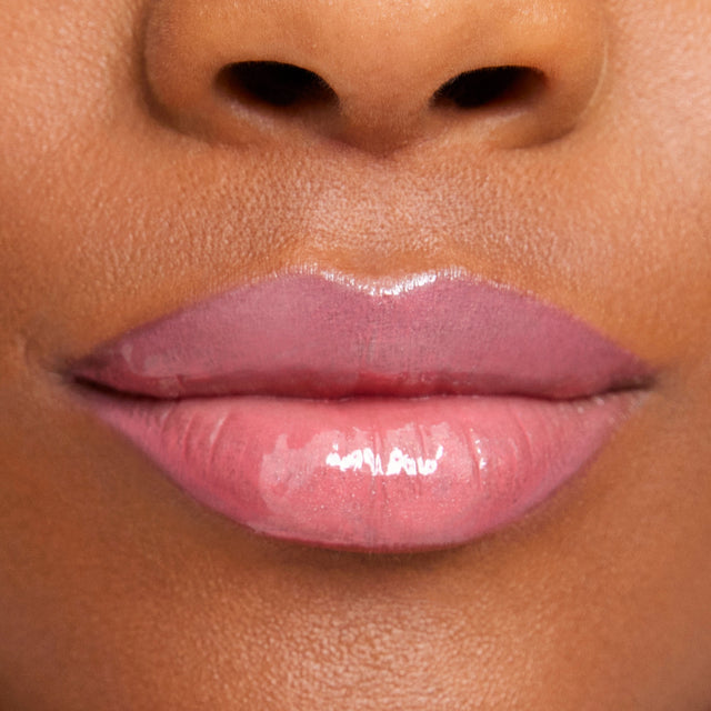 Deep skin tone model wearing Wet Lip Oil Gloss in Malibu