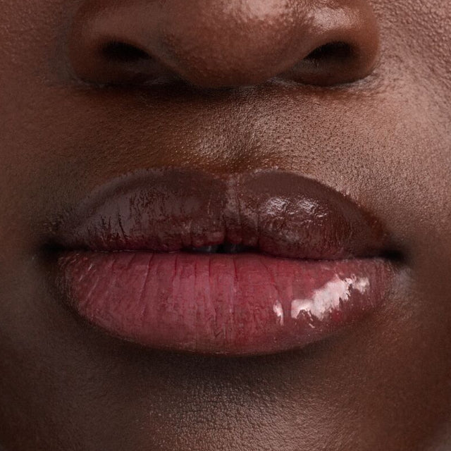 Deep skin tone model wearing Wet Lip Oil Gloss in Slushy
