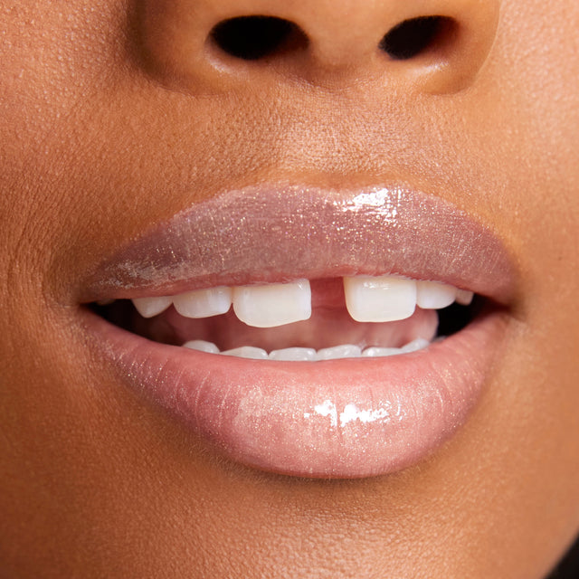 Deep skin tone model wearing Wet Lip Oil Gloss in Unzipped
