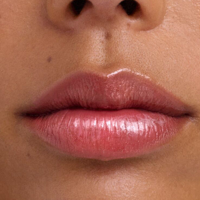 Medium skin tone model wearing Wet Lip Oil Gloss in Grapesicle