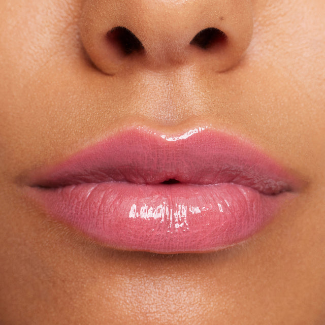 Medium skin tone model wearing Wet Lip Oil Gloss in Malibu