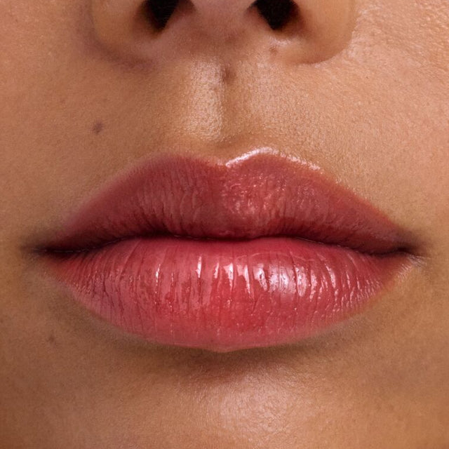 Medium skin tone model wearing Wet Lip Oil Gloss in Slushy