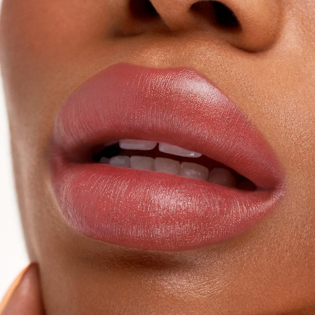 Deep skin tone model wearing Weightless Lip Color in Stardust
